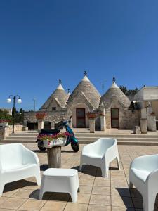 a scooter parked in front of a building with white chairs at Trulli del boschetto in Putignano