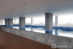 a large swimming pool with blue tiles and columns at Minimalist Studio at Poris 88 Apartment By Travelio in Tangerang