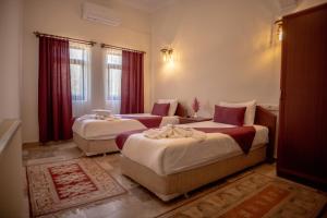 two beds in a hotel room with red curtains at Güven Cave Hotel in Goreme