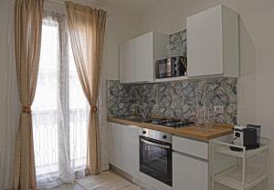 a kitchen with white cabinets and a stove and a window at CasAmuri Exclusive Apartments in Noto +25 photos