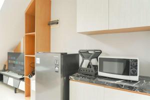 a kitchen with a refrigerator and a microwave at Studio Loft No Kitchen Mezzanine at Kubikahomy Apartment By Travelio in Tangerang