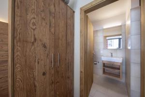 a bathroom with a sink and a wooden door at Edelweisshaus Top 8 in Königsleiten +29 photos
