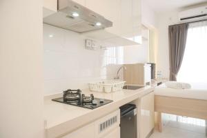 eine weiße Küche mit Spüle und Herd in der Unterkunft Best Choice and Nice Studio at Sky House BSD Apartment By Travelio in Tangerang