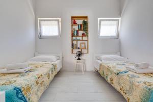 two beds in a room with white walls and windows at Geräumige Ferienwohnung im Erdgeschoss mit Meerblick vom privaten Balkon in Kožino