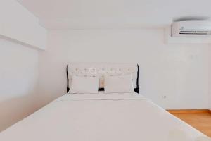 a white bed with two pillows in a room at Modern and Comfort Look Studio Kingland Avenue Apartment By Travelio in Tangerang