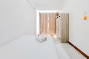 ein weißes Schlafzimmer mit einem Bett und einem Fenster in der Unterkunft Modern Look 1BR Apartment at Scientia Residence By Travelio in Tangerang + 14 Fotos
