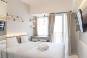 ein Schlafzimmer mit einem weißen Bett mit zwei Handtüchern darauf in der Unterkunft Comfort Studio Room Tokyo Riverside PIK 2 Apartment By Travelio in Rawalembang