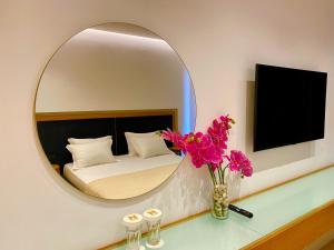 a mirror in a room with a bed and flowers at Hotel Nertili in Sarandë