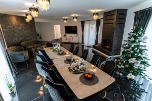 a dining room with a table and a christmas tree at DAR House in Vîlcele