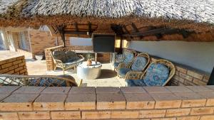 a patio with chairs and a thatch roof at First 2 Stay in Germiston