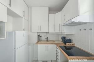 a white kitchen with white cabinets and a sink at Flexliving - room - Lindet in Paris