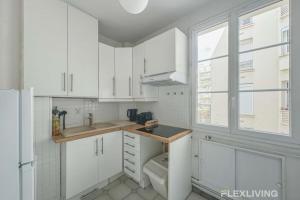 a kitchen with white cabinets and a sink and a window at Flexliving - room - Lindet in Paris