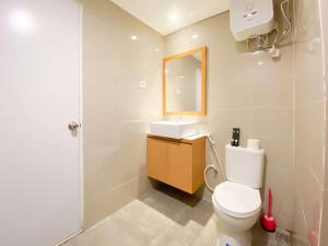 a bathroom with a toilet and a sink and a mirror at Cozy Living Studio (No Kitchen) at Sentraland Semarang Apartment By Travelio in Semarang