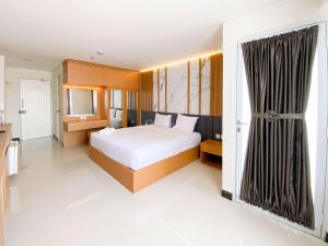 a bedroom with a large white bed and a window at Cozy Living Studio (No Kitchen) at Sentraland Semarang Apartment By Travelio in Semarang