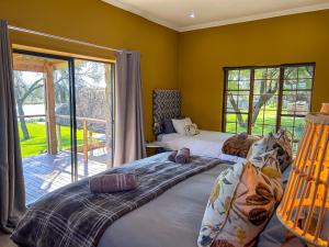 two beds in a room with yellow walls at Tzamenkomst River Lodge in Colesberg