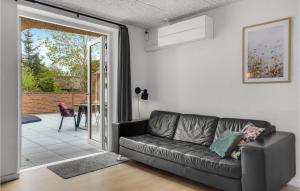 Sofá negro en la sala de estar con puerta corredera de cristal en Lovely Home In Ulfborg With Sauna, en Ulfborg