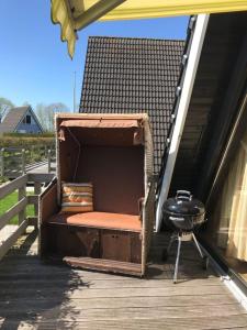 a bench sitting on a porch with a grill at Ferienhaus in Fedderwardersiel mit Terrasse in Butjadingen