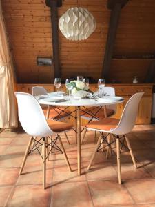 a dining table with white chairs and a light fixture at Ferienhaus in Fedderwardersiel mit Terrasse in Butjadingen +10 photos