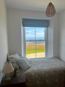 ein Schlafzimmer mit einem Bett und einem großen Fenster in der Unterkunft The Moorings - Just a few metres from the sea! in Padstow