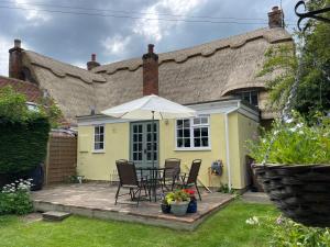 ein gelbes Haus mit einem Tisch und einem Regenschirm in der Unterkunft Buttercup Cottage, Hartest in Hartest