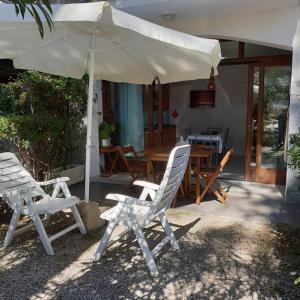 un patio con dos sillas y una sombrilla en il faretto casale grandangolo, en Capoliveri
