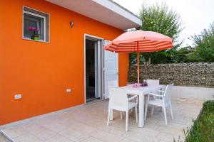 an orange house with a table and an umbrella at Casa Vacanza Mario 1A a 180 mt dal mare di Punta Prosciutto in Punta Prosciutto