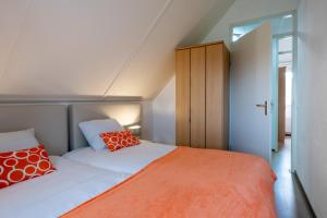 ein Schlafzimmer mit einem Bett mit orangefarbenen und weißen Kissen in der Unterkunft Antibes 198 - Kustpark Village Scaldia in Hoofdplaat