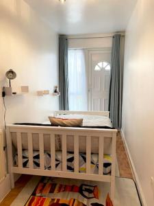 a crib in a room with a window at Crescent 2 Bedroom Apartment in Goodmayes