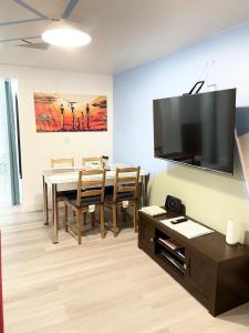 a living room with a table and a television on a wall at Crescent 2 Bedroom Apartment in Goodmayes