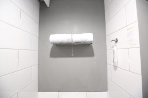 un bagno bianco con due asciugamani su uno scaffale di Hotel Citradream Bintaro a Serpong