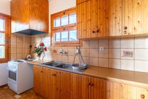 a kitchen with wooden cabinets and a sink at Spacious Cottage - Panoramic Sea & Mountain Views in Ano Doloi +18 photos