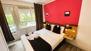 ブローニュ・シュル・メールにあるHôtel OpalOrientalの赤い壁のベッドルーム1室(大型ベッド1台付)