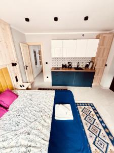 a bedroom with a blue bed and a kitchen at Studio dla 2 osób Tatra-Dream in Zakopane