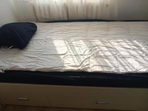 1 cama con sábanas blancas y almohada azul en Apartman MDj, en Žarkovo