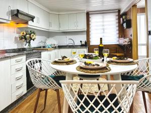 a white kitchen with a table with glasses of wine at As Carolinas in Isla de Arosa +39 photos