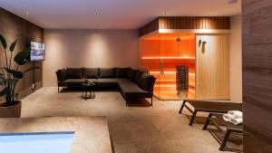 a living room with a black couch and a table at Veluwe Villa met Binnenzwembad & Wellness - 12 personen - Resort Valley in Wekerom