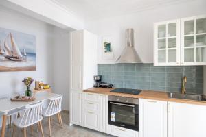 a kitchen with white cabinets and a table and a sink at Para Thin Alos Skiathos in Skiathos