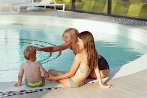 a woman and a child sitting next to a swimming pool at Thalazur Arcachon in Arcachon