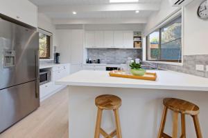 a kitchen with white cabinets and a large island with stools at Brooks by the bay in Blairgowrie