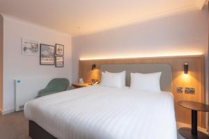 a hotel room with a large bed and a chair at Holiday Inn Brentwood by IHG in Brentwood