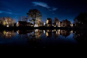 Una vista nocturna de un lago con casas y árboles. en Villa Zon & Duin, en Egmond aan den Hoef