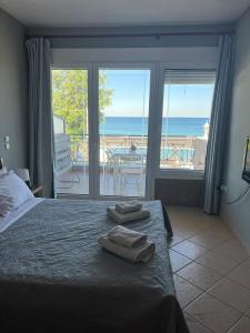 a bedroom with a bed and a view of the ocean at Glykanisos Mini Suites in N&eacute;a P&eacute;ramos