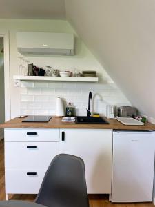 a kitchen with white cabinets and a black chair at Quiet, green, relaxing place - 1 bedroom apartment in Balatonfüred