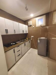 a small kitchen with white cabinets and a refrigerator at رست بست للشقق المخدومة in Al Mikhlaf