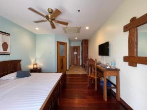 a bedroom with a bed with a ceiling fan and a desk at Corto del Mar Hotel in Coron