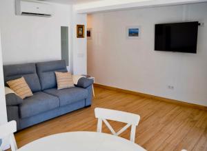 een woonkamer met een blauwe bank en een flatscreen-tv bij Casa Albita Calpe in Calpe
