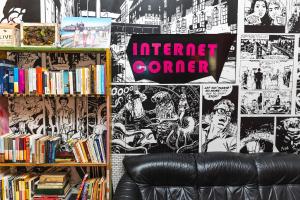 a room with a leather couch and posters and books at Hostel Link in Lovran