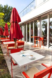 a patio with tables and chairs and a red umbrella at Hostel Link in Lovran
