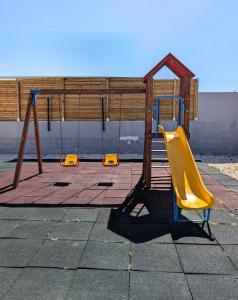 un parco giochi con uno scivolo giallo e una recinzione di legno di Apartamento da Praia a Sagres