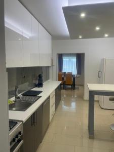 a kitchen with white cabinets and a sink and a table at Kuća za odmor Mariola in Karlovac